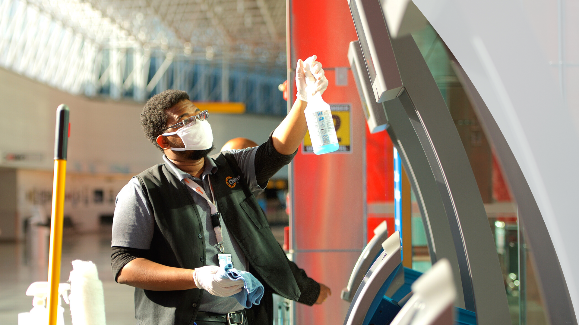 Photograph of Chimes custodial worker spraying cleaning product onto a ticketing/check-in kiosk at BWI Marshall Airport